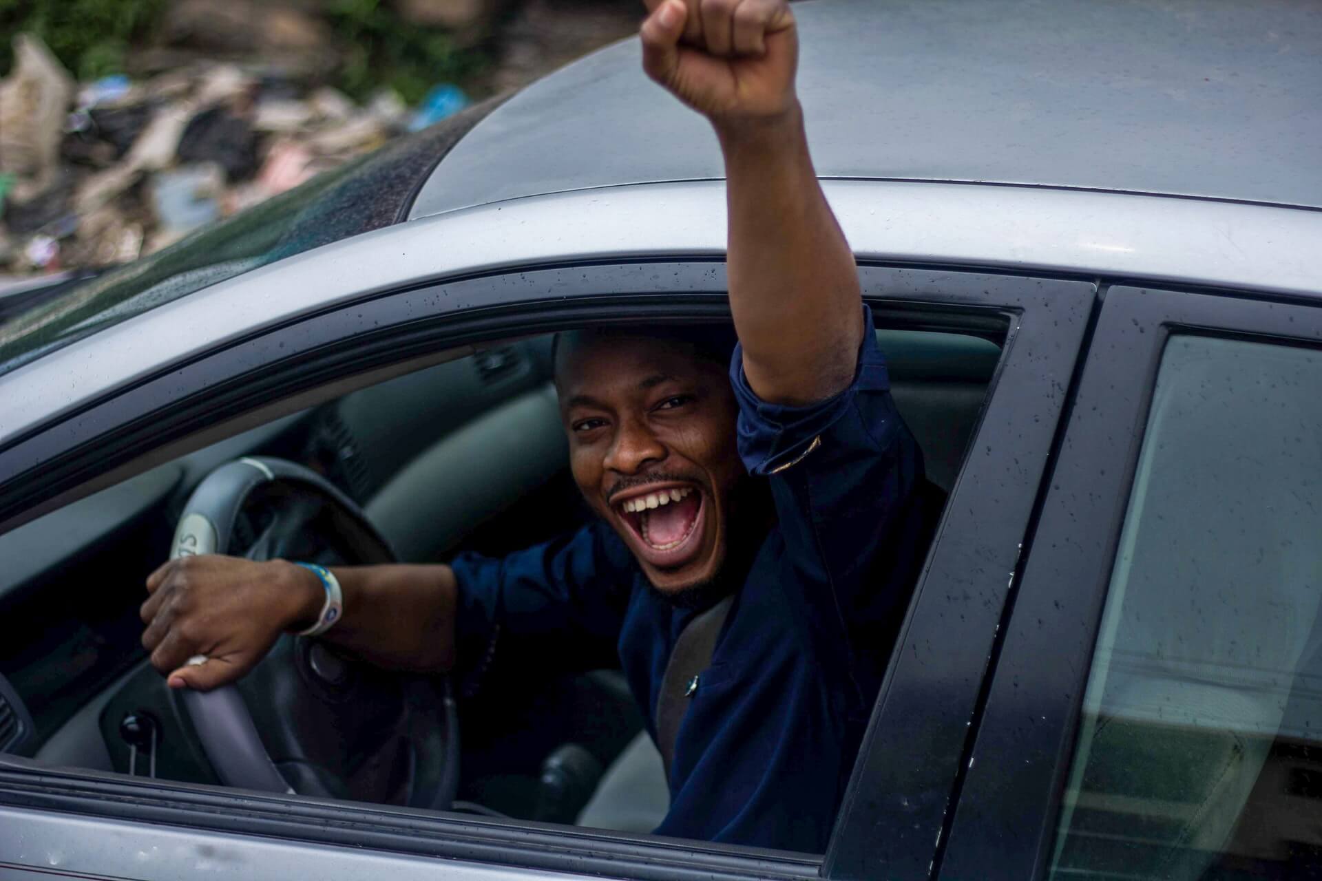 Jeune homme avec le poing levé au volant d'une voiture